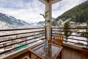 a balcony with a table and chairs and mountains at Manali Parvat View in Jagatsukh