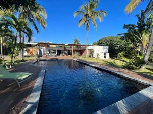 a swimming pool in front of a house with palm trees at Maison Nature in La Possession