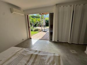 a bedroom with a bed and a sliding glass door at Maison Nature in La Possession