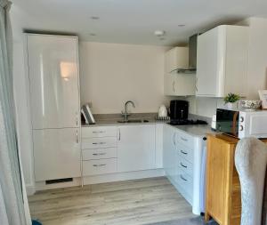 a kitchen with white cabinets and a sink at Cotswold studio with kitchen & patio in Witney +9 photos