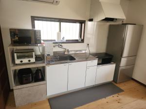 a kitchen with white cabinets and a stainless steel refrigerator at 古民家宿懐 in Nachikatsuura +25 photos