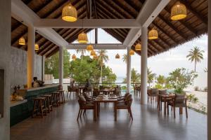a restaurant with tables and chairs and a view of the ocean at Le Baoli Koh Rong in Phumĭ Kaôh Rŏng
