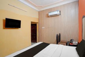 a bedroom with a bed and a tv on the wall at Hotel O Charbagh Metro Station Formerly Siddhi Paradise in Lucknow