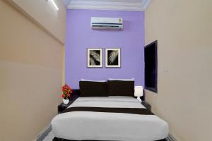a bedroom with a large bed with a purple wall at Hotel O Charbagh Metro Station Formerly Siddhi Paradise in Lucknow +31 photos