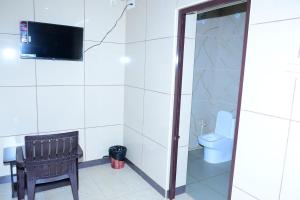 a bathroom with a toilet and a tv on the wall at ARS INN AND MINI HALL Vellore in Vellore +3 photos