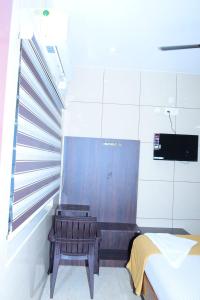 a room with a bench and a bed and a tv at ARS INN AND MINI HALL Vellore in Vellore