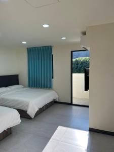 a bedroom with two beds and a large window at Travel Island B&B in Beigan