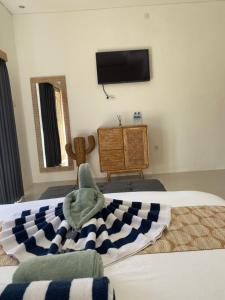 a bedroom with two beds and a television on the wall at Ramaiin guest house in Nusa Dua