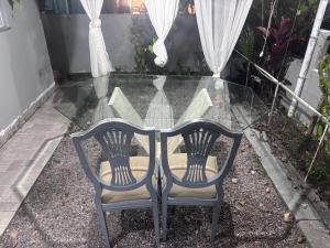 a glass table with two chairs in front of a window at Praia do sonho, Quarto para até 4 pessoas super aconchegante in Palhoça