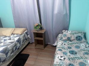 a room with two beds and a table with a bed and a table sidx sidx at Praia do sonho, Quarto para até 4 pessoas super aconchegante in Palhoça