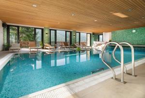 a large pool with chairs and tables in a building at Hotel Adam in Špindlerův Mlýn