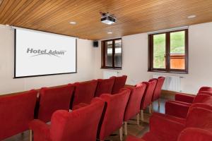 a lecture room with red chairs and a screen at Hotel Adam in Špindlerův Mlýn