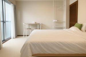 a white bedroom with a bed and a table at 旅館ほのか in Osaka