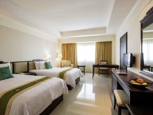 a hotel room with two beds and a television at Mercure Chiang Mai in Chiang Mai
