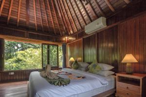 a bedroom with a bed and a large window at Abangan Bungalow in Ubud +123 photos