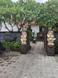 a garden with two stone statues in front of a building at Jukung Villas Kuta in Kuta