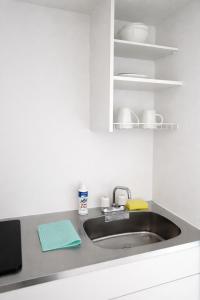 a kitchen counter with a sink and a shelf at 旅館ほのか in Osaka