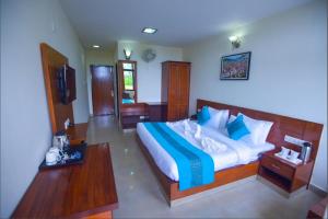a bedroom with a large bed with blue and white pillows at Hotel Rongla in Pālampur +20 photos