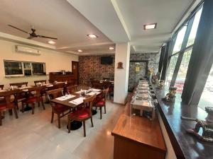 a restaurant with wooden tables and chairs and windows at Hotel Rongla in Pālampur
