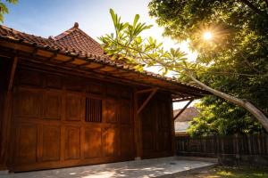 a wooden garage with a fence and a tree at Dapur Alit Villas in Yogyakarta