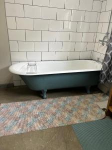 a bath tub in a bathroom with white tiles at Geckos Rest Southbroom in Southbroom +9 photos