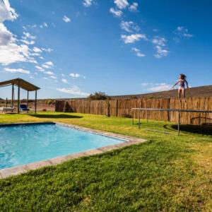 a person standing on a fence next to a swimming pool at Jagerskraal Guest Farm in Laingsburg