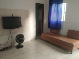 a living room with a couch and a tv and a fan at 3-bedroom house on Cabuçu beach in Saubara