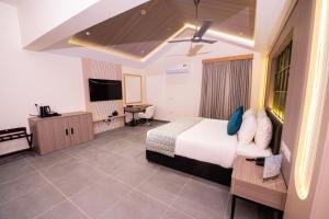 a hotel room with a bed and a flat screen tv at Esthell Village Resort in Mahabalipuram