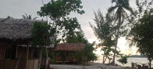 a house with a straw roof next to the water at Sawinsrom Homestay in Fam +6 photos