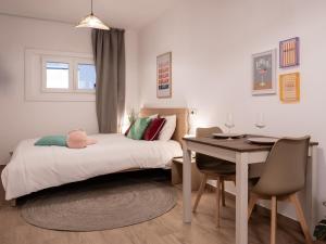 a bedroom with a bed and a table and a desk at Studio chic proche aéroport et centre-ville in Charleroi