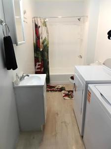a white bathroom with a sink and a shower at Cosy single-level home with laundry and parking in Huntington +14 photos