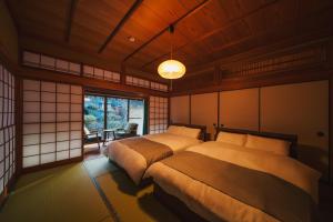 a bedroom with two beds and a large window at アリュール照波園 in Beppu +25 photos