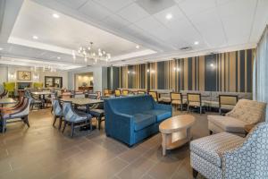 a restaurant with tables and chairs and a blue couch at The Clocktower Hotel Latham - North Albany, an Ascend Collection Hotel in Cohoes