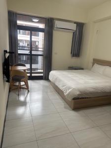 a bedroom with a bed and a chair and a window at Royal Court B&B in Donggang