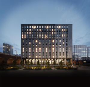 a tall building with lights on in a city at Hyatt House Aparthotel Leeds in Leeds
