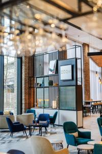 a lobby with chairs and tables and a tv at Hyatt House Aparthotel Leeds in Leeds