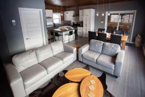 a living room with couches and a table and a kitchen at Lakefront - Chalet Le Missionnaire in Trois Rives
