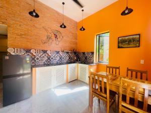 a kitchen with orange walls and a table and a refrigerator at Orange Villa Muine in Mui Ne