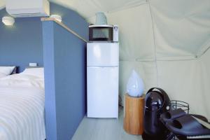 a room with a white refrigerator and a bed at Shinon 森音 in Tateyama