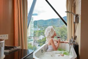 a woman sitting in a bath tub with a glass of wine at Nimman Mai Design Hotel Chiang Mai in Chiang Mai