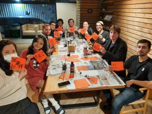 a group of people sitting around a table holding up orange signs at MEANDER Taipei in Taipei