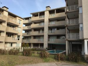 an apartment building with a swimming pool in front of it at Solo Pinamar in Pinamar