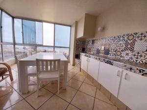 a kitchen with a white table and chairs and windows at Margate Boulevard Beachfront Apartment in Margate