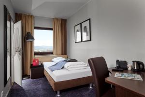 a hotel room with a bed and a desk and a window at Hotel Cabinn Vejle in Vejle