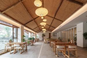a restaurant with wooden tables and chairs and windows at Xianzai Houshe Boutique Hotel in Dujiangyan