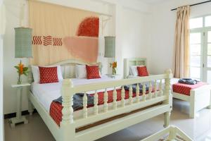 a bedroom with two beds with red pillows at Mira Mirissa in Mirissa