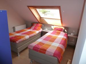 two beds in a small room with a window at Vakantiehuis 'De Wulpenbrug' in Wulpen