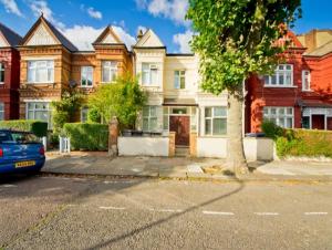 una casa con un coche aparcado delante en London Queen Park Apartments, en Londres