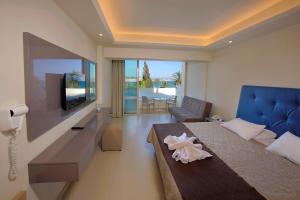 a bedroom with a bed and a tv and a couch at Nelia Beach Hotel & Spa in Ayia Napa