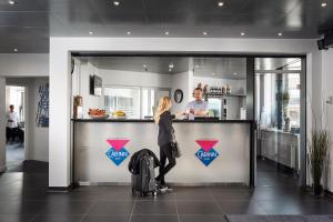 a woman standing at a counter in a restaurant at Hotel Cabinn Vejle in Vejle